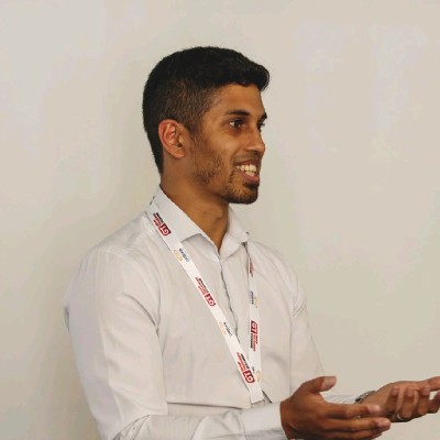 Amar Farooq_Photo Man in white shirt smiling and gesturing with hands, possibly at Ask-The-Treasurer event