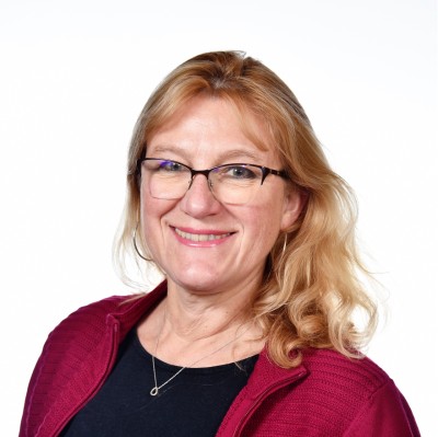 Catherine Porter_Photo Portrait of a smiling woman with blonde hair and glasses, likely a speaker at an event