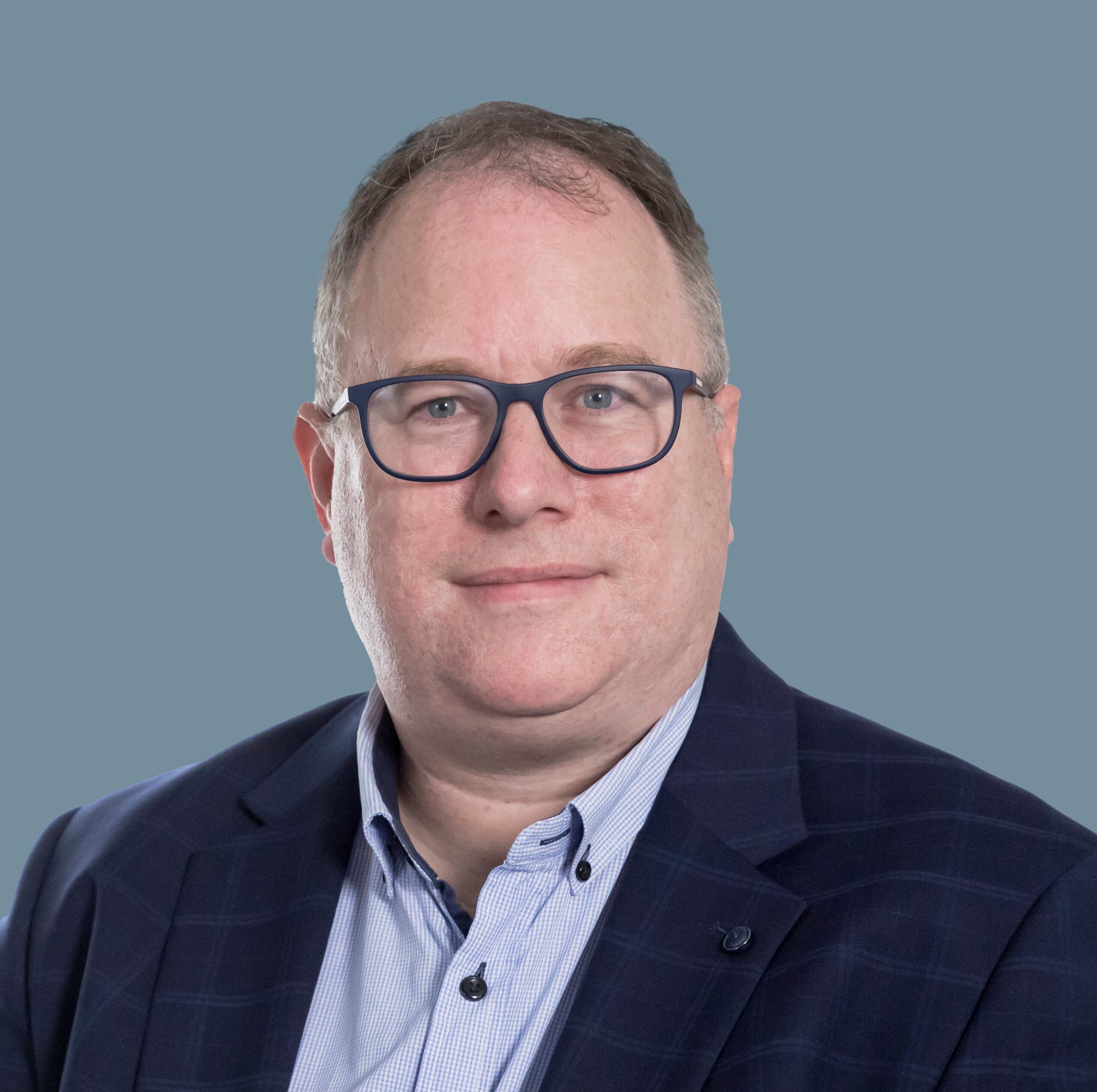 Luke Maclean Man in business suit and glasses speaking on AI in Treasury